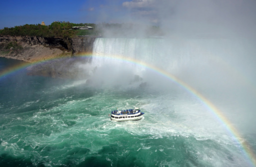 Tour boat visiting Niagara Falls under rainbow