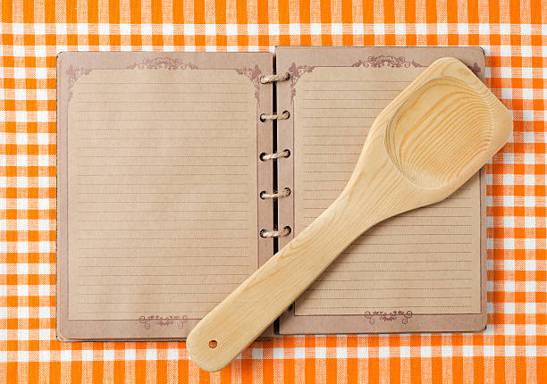 Wooden spoon and old notebook on orange tableclot.