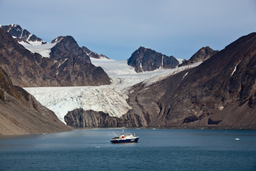 Arctic landscape in Spitzbergen -Svalbard. View across the Krossfjord to the mountains and glaciers on the other side of the Fjord. Passenger ship is anchoring in the fjord