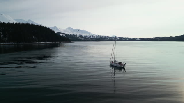 Aerial view around a sailboat moored in calm waters of Zaikol bay, Alaska