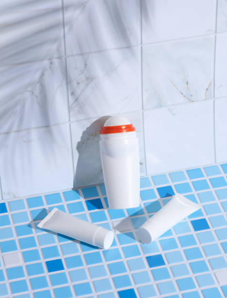istock Antiperspirant stick and cream tubes on tile with palm leaf shadow. Creative layout. Beauty still life 1849686935