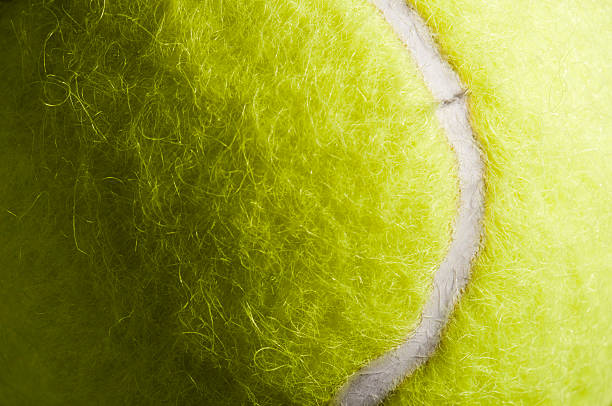 Detail and texture of yellow tennis ball and rubber marking Cropped section of a fluffy yellow tennis ball tennis ball stock pictures, royalty-free photos & images