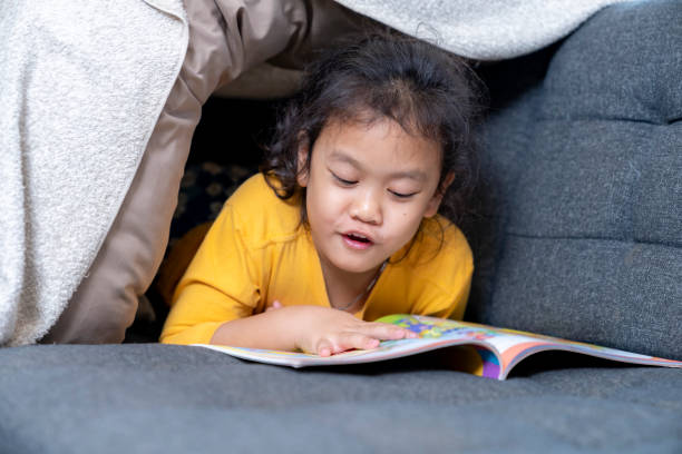 istock A girl is sitting on the sofa at home, reading a book 1849708135