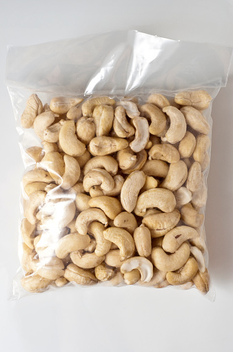 Unpeeled almonds in a package with a zipper. Isolated on wooden background with clipping paths.