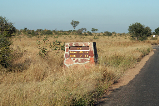 Sturdy built roadside sign built to withstand damage by elephants, showing direction and distance to camps in Kruger National Park, South Africa
