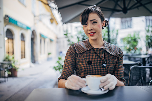 Modern young woman sitting on coffee break outdoors in cafe in Vienna.
