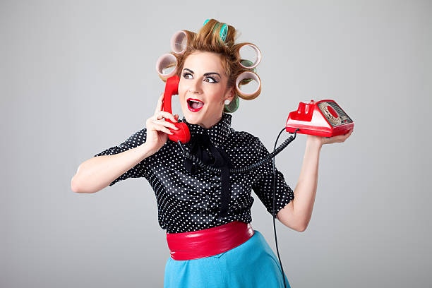 Portrait of retro housewife having interesting chat over old fashioned red phone