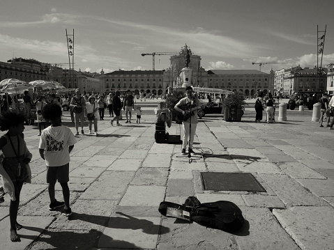 Lisbon, Portugal - June 10, 2023: A street musician plays a guitar at the Praça do Comércio square in Lisbon downtown.