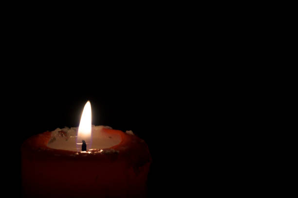 istock Burning red candle flame with dark background in lower left horizontal with area for copy space 1849720387
