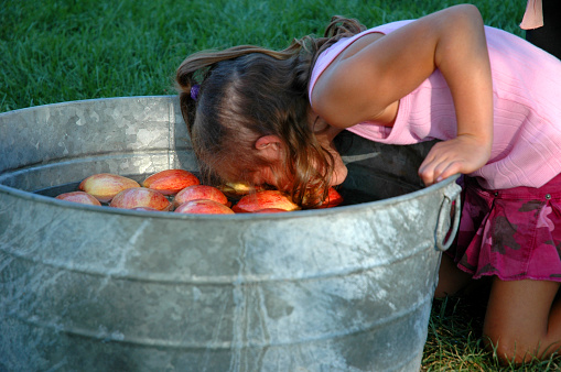 Little girl bobbing for apples at her birthday party