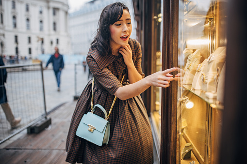 Modern young woman window shopping for jewelry in Vienna.