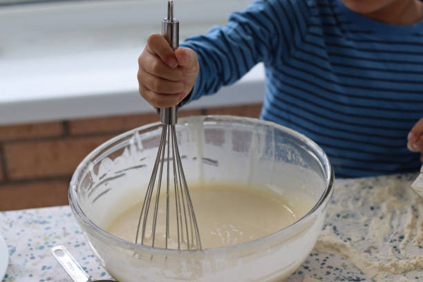 Child mixing cake batter for making waffle cake at home