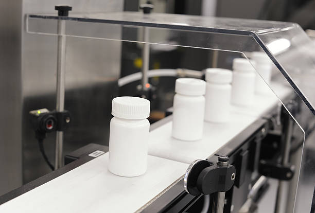 Drug Manufacturing Shot of unlabeled drug bottles traveling along a conveyor in a pharmaceutical manufacturing facility. drug manufacturing stock pictures, royalty-free photos & images