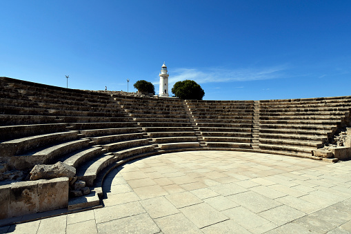 Paphos, Cyprus - October 02, 2023: Odeon Amphitheater and Paphos Lithghouse in archaeological area of Kato Paphos - a UNESCO world heritage site, Paphos aka Pafos was European Capital of Culture in 2017