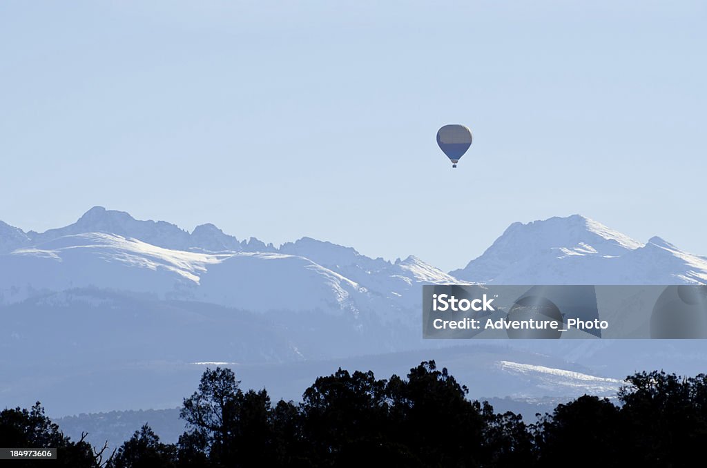 Hot Air Balloon with Dramatic Mountain Scenery in Winter Hot Air Balloon with Dramatic Mountain Scenery in Winter.  Sawatch Range mountains with hot air balloon floating mid-air in the mountains with snowcapped jagged peaks.  Captured as a 14-bit Raw file. Edited in ProPhoto RGB color space. Hot Air Balloon Stock Photo