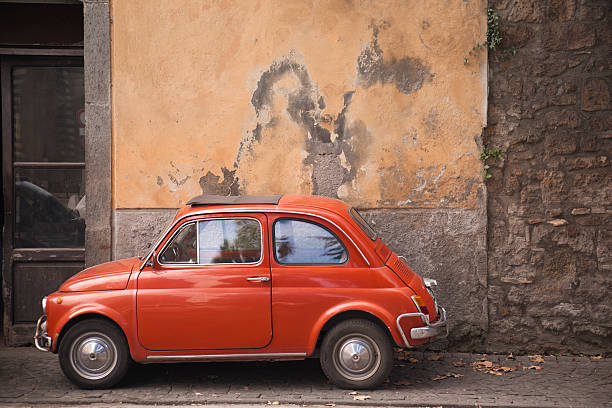 istock Orange vintage Italian car parked against a rusty wall 184973995