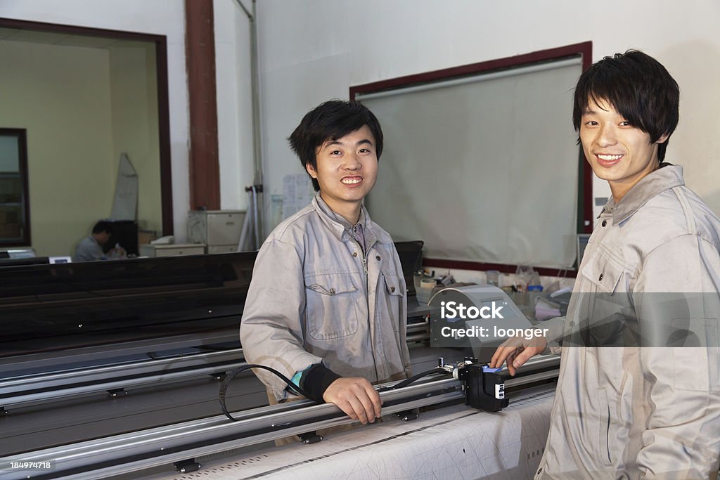 East asian workers operating the printer "East asian workers operating the printer in the wide format Industrial Inkjet printer workshop, Beijing, China" Factory Stock Photo
