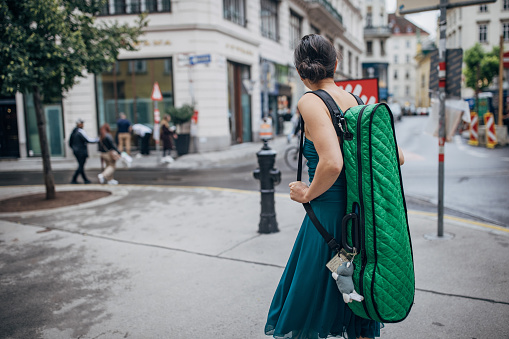Young woman musician with violin case walking the streets in Vienna.