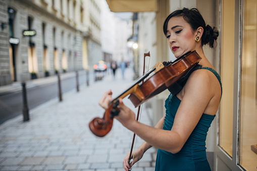 Young woman violinist playing the violin on the street in Vienna.