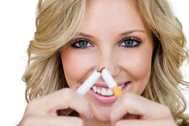 Cheerful woman breaking a cigarette for a stock smoking concept 