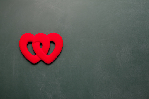 Red heart shape on green blank blackboard.The red hearts are on the left side of frame.Copy space on the right side.Shot with a full frame DSLR camera 