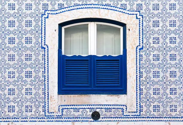 "Typical window with beautiful tiles and blue wooden closed shutters. Was seen in the City of Lisbon. These tiles are named in Portugal Azulejo. Azulejo is a form of Portuguese or Spanish painted, tin-glazed, ceramic tilework.For more pictures, please look here:"