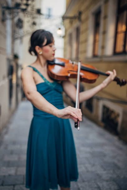 Female violinist playing a violin outdoors in a music pavilion or bandstand. About 25 years old, Caucasian woman.