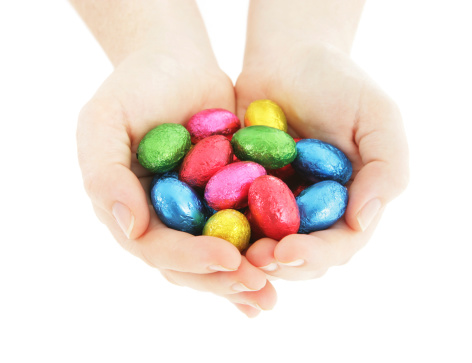 A woman's hands holding colourful Easter eggs.  Isolated on white.