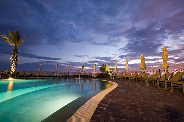 Swimming pool at sunrise in front of a luxury hotel, sea in background.
