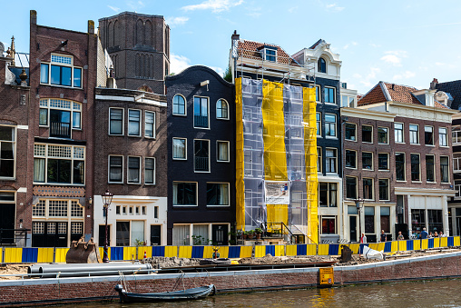 Amsterdam, Netherlands - August 12, 2017: A building under construction in Amsterdam is covered with a striped protective material.