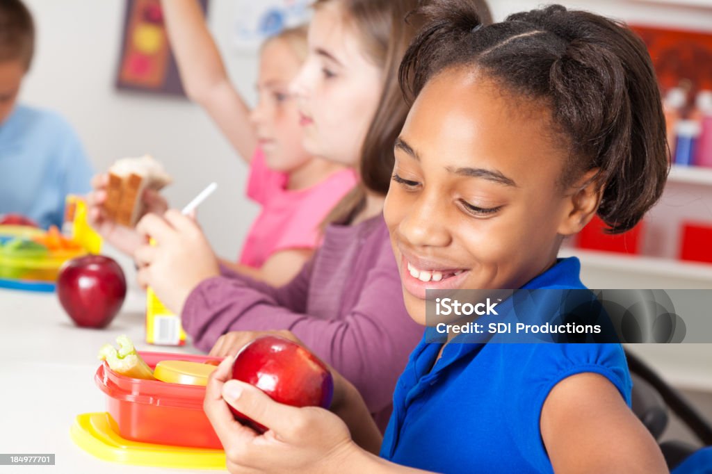 Menina bonita comendo um almoço no escola - Foto de stock de Cantina royalty-free