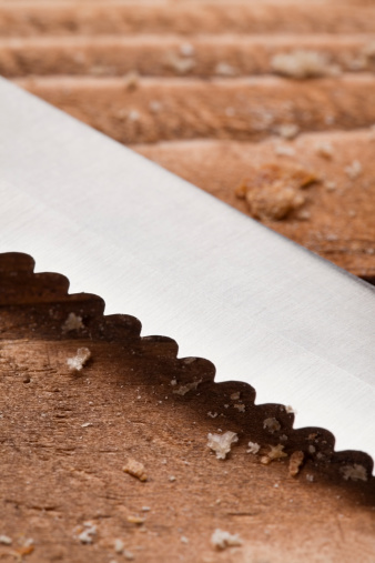 Bread knife on the wooden plank as background with few crumbs around; Adobe rgb color spacesee other similar images: