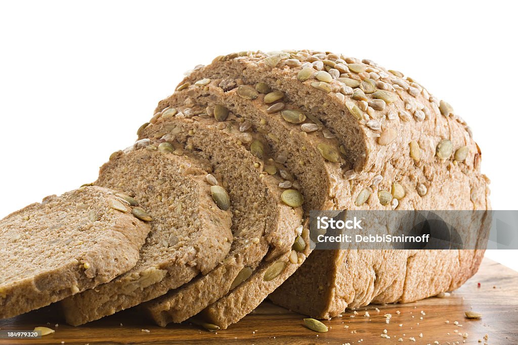 Multi Grain Bread A close up of a partially sliced loaf of a healthy multi grained bread on a wooden cutting board. Against a white background. Baked Stock Photo