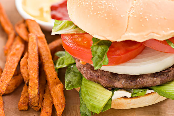 Cheeseburger on a whole wheat bun with crinkle cut sweet potato fries
