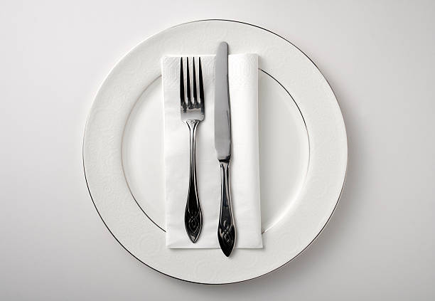 eating utensils on a white plate against a white background - bestek stockfoto's en -beelden