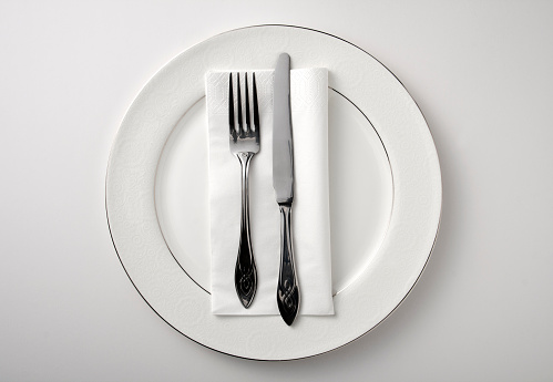 Eating utensils on a white plate against a white background
