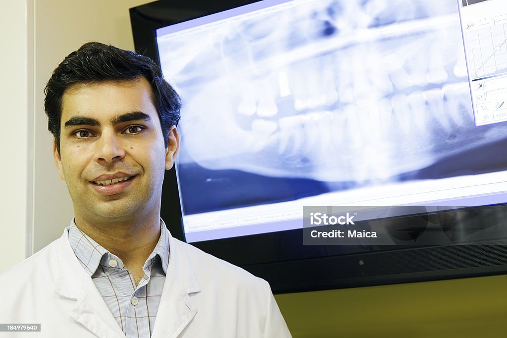 Dentist "Dentist posing in front of an screen that shows a dental x-ray image. Real dentist, not a model." 30-39 Years Stock Photo