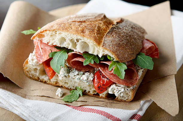 Artisan Salami Sandwich "Rustic sandwich of salami, roasted red peppers, arugula, and herbed goat cheese on ciabatta bread.  Very shallow DOF.MORE IMAGES:" sandwich stock pictures, royalty-free photos & images