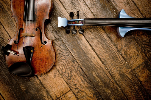 A vintage violin siding up against a modern electric violin on a wooden floor. Canon 1Ds Mark 2 file