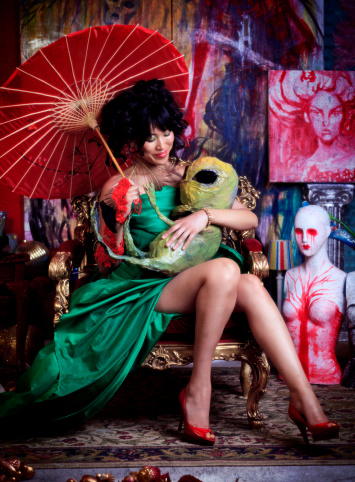 Beautiful woman wearing a green dress and holding a green alien baby.