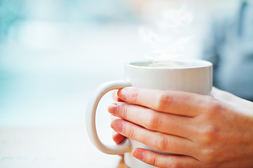 caucasian woman holding hot mug of coffee