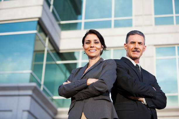 бизнесмен и деловая женщина, стоя за пределами офисное здание - two people back to back businesswoman women стоковые фото и изображения