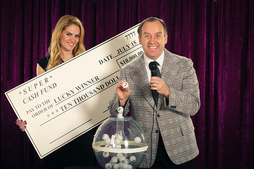 A Retro color processed lottery drawing show host with his lovely assistant. Photographed in studio with a purpose built set and props.
