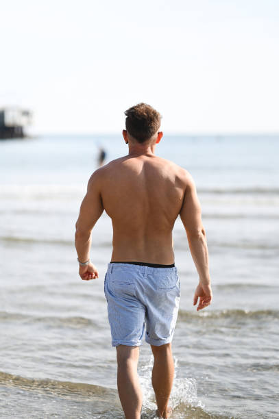 istock Rear view of handsome muscular man on a seacoast. 1849821509