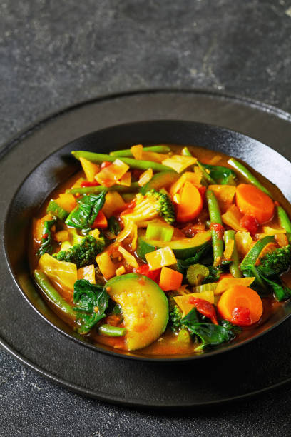 istock vegetable soup with green beans, broccoli, carrot, celery, spinach, cabbage, onion, tomatoes in black bowl 1849824133