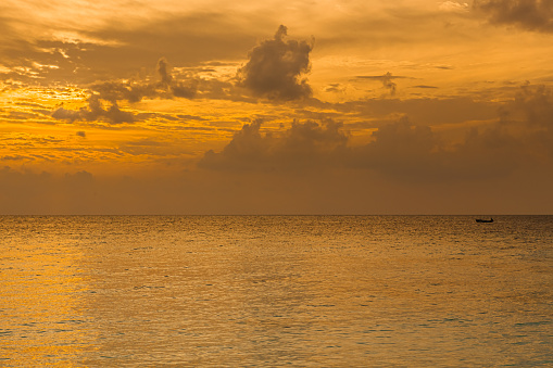 Photo of a lone boat in the ocean at sunset. Maldives
