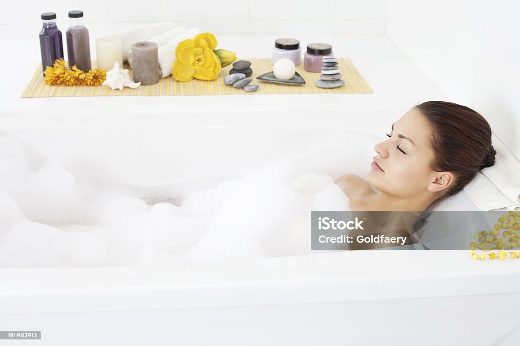Beautiful young woman relaxing in bathtub. Beautiful young woman relaxing in bathtub with her eyes closed. 20-29 Years Stock Photo