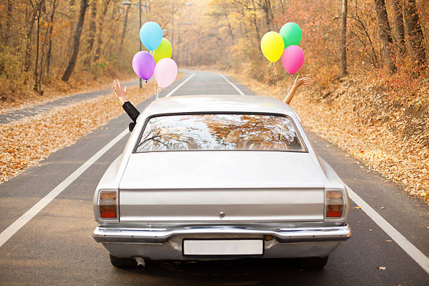 a couple just married with balloons tied to their car - nygift bildbanksfoton och bilder