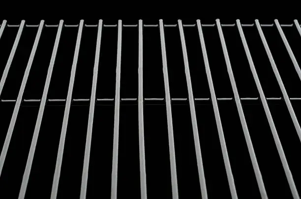Black oven rack over pure black background. Can be used for placing baked dishes on(as if in the oven)or cooling.Additional black can be added vertically for copy space. could also be used to depict grilling.