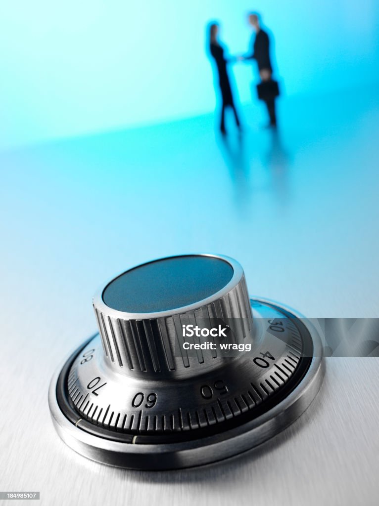 Bank Vault and Business Agreement Bank safe dial on stainless steel.  Business people shaking hands in the background with copy space.Click on the link below to see more of my business and security images. Handshake Stock Photo